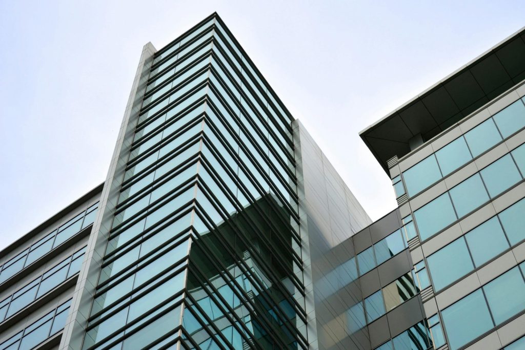 Low angle view of a modern skyscraper with glass facade reflecting the sky.